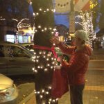 Volunteer Liam helps to hang scarves along Washington Street