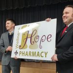 Lester Burris, at left, and J.T. Doane unveil the sign for the new Hope Wellness Pharmacy.